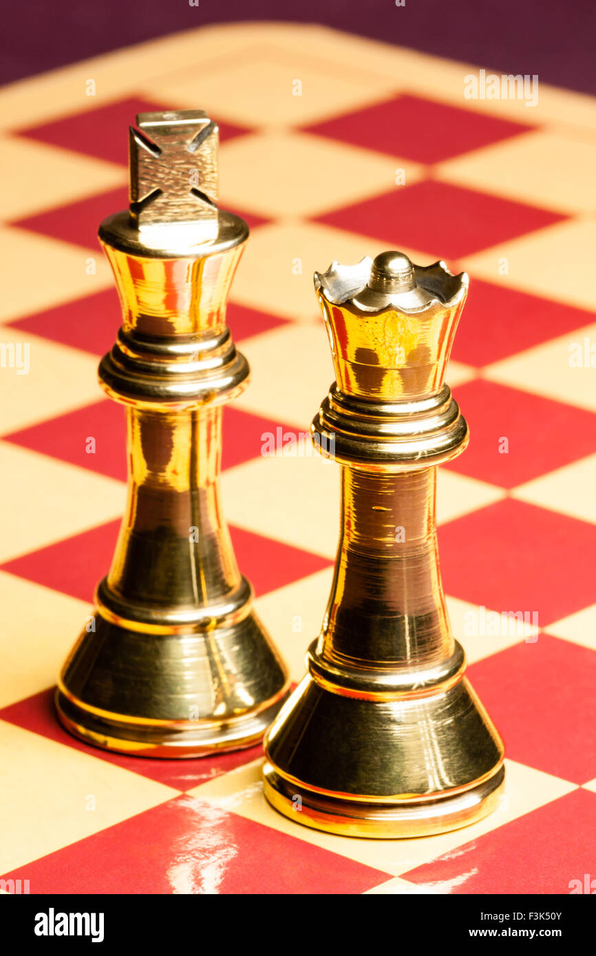 Old brass chess queen and king pieces on a chess board. Shallow DOF used. Stock Photo