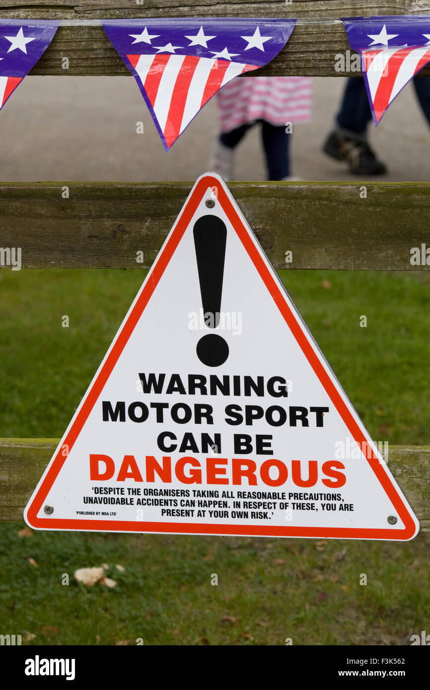 Public information Sign warning the public that Motor sports can be dangerous with American flag bunting Stock Photo