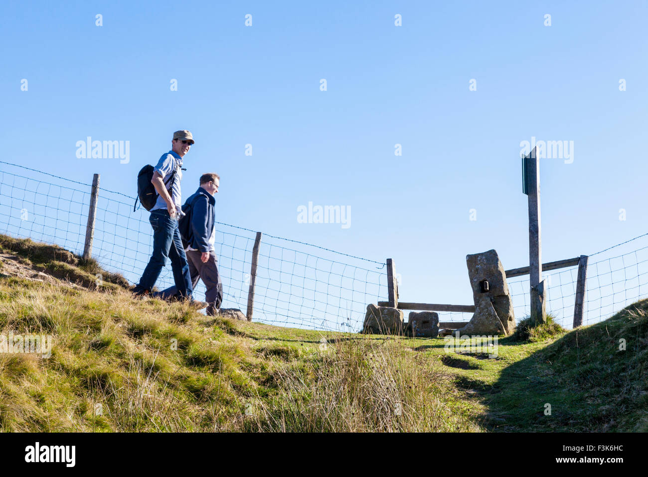 Rambling in the English countryside. Ramblers walking down a hill towards a stile on The Great Ridge, Derbyshire, Peak District, England, UK Stock Photo