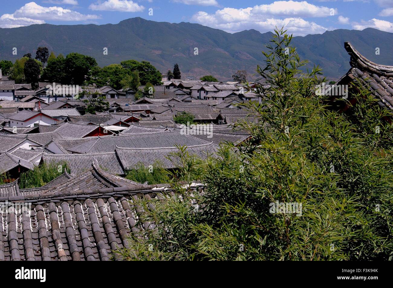 Lijiang, China:  View over the slate gray tiled roof centuries-old Naxi houses to distant mountains Stock Photo