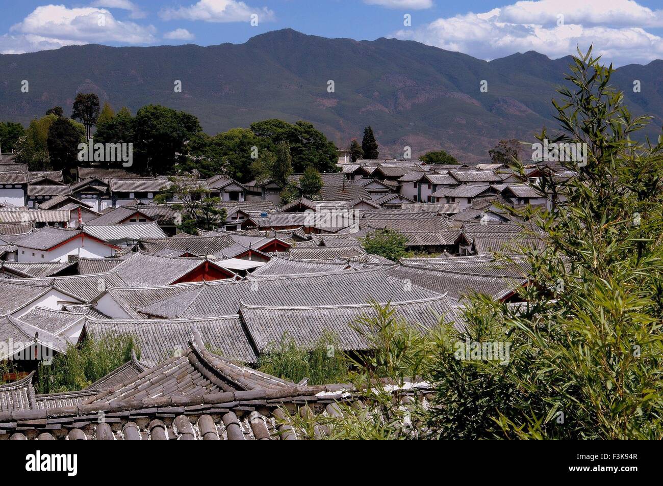 Lijiang, China:  View over centuries-old Naxi homes with their slate gray tiled roofs and distant mountains Stock Photo