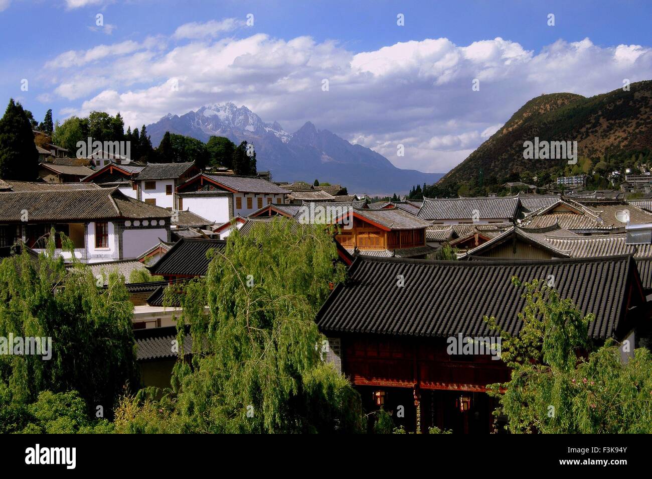 Lijiang, China:  View over ancient Naxi homes with tiled roofs to distant Jade Dragon Snow Mountain Stock Photo