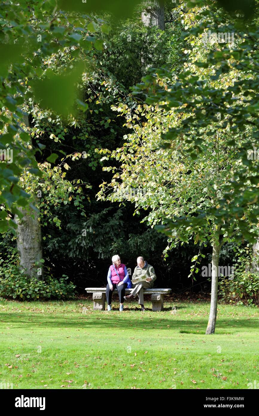 Mature couple sitting on stone bench in parkland Stock Photo - Alamy