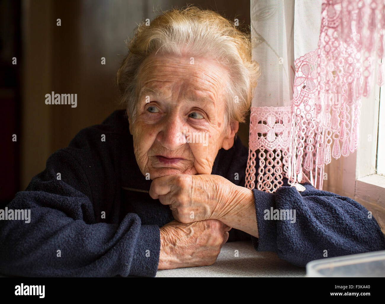 Elderly woman sitting at table in the house. Stock Photo