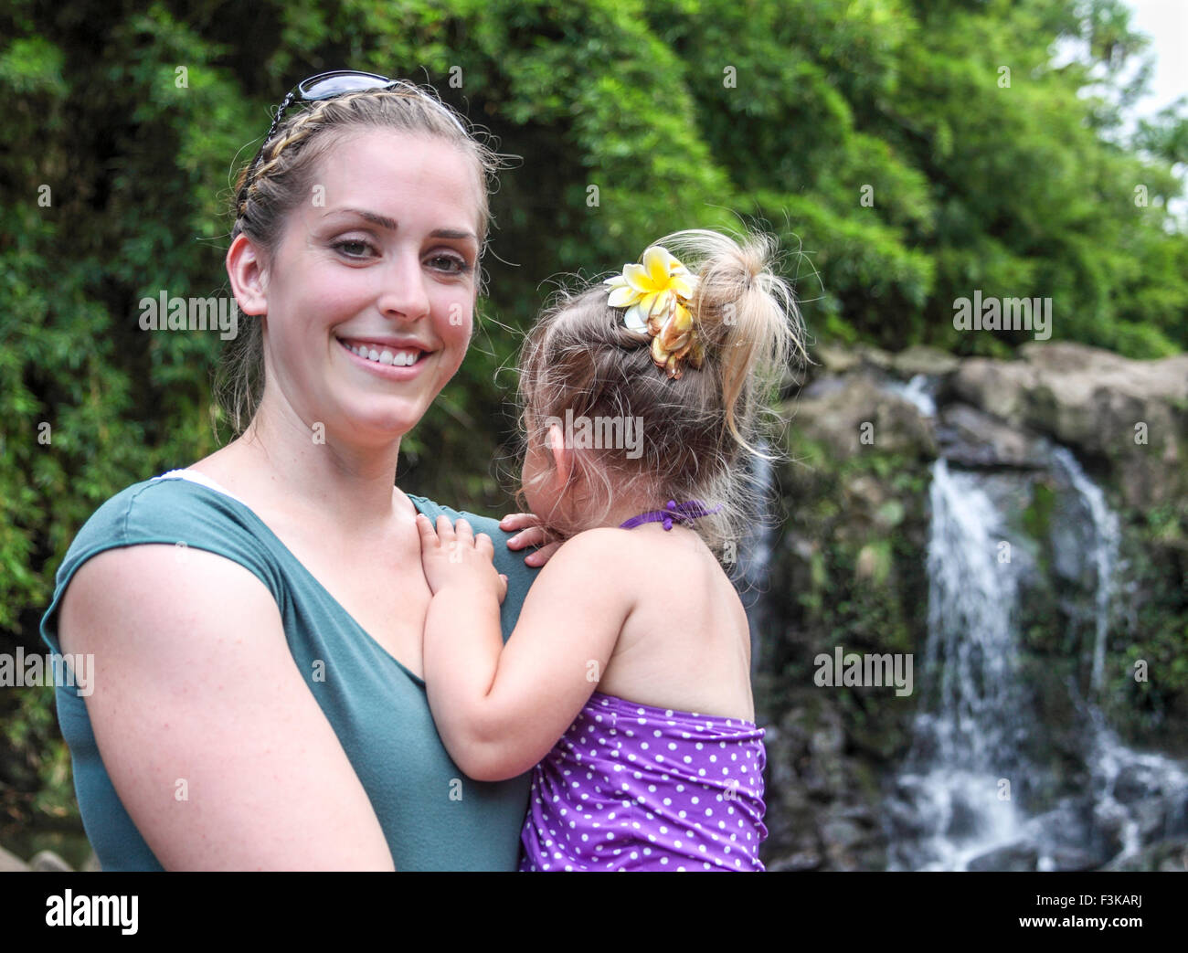 Mother and daughter by waterfall reached by hike in Maui Stock Photo
