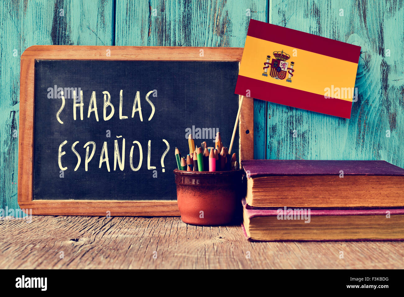 a chalkboard with the question hablas espanol? do you speak Spanish? written in Spanish, a pot with pencils and the flag of Spai Stock Photo