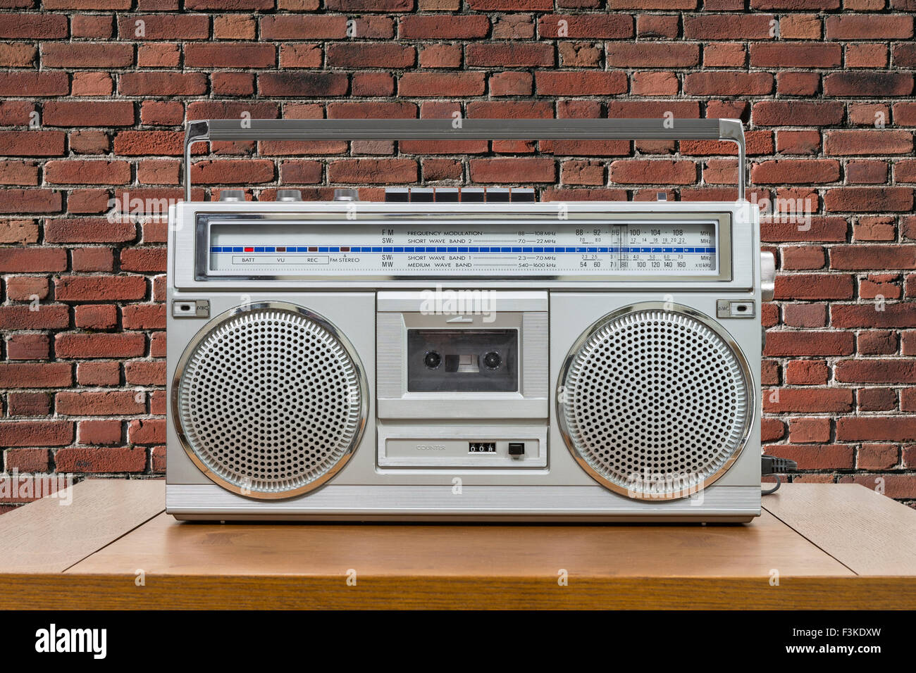 Vintage boombox on wood table with red brick wall. Stock Photo
