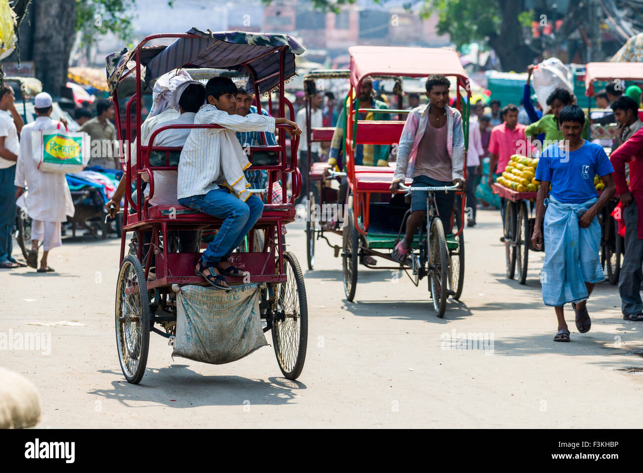 Many people and cycle rikshaws are moving through the streets of the suburb Old Delhi Stock Photo