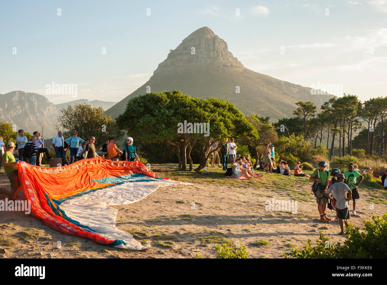 People gathered on top of Signal Hill at sunset, with Lion's Head in distance, to watch paragliders take off from Table Mountain Stock Photo