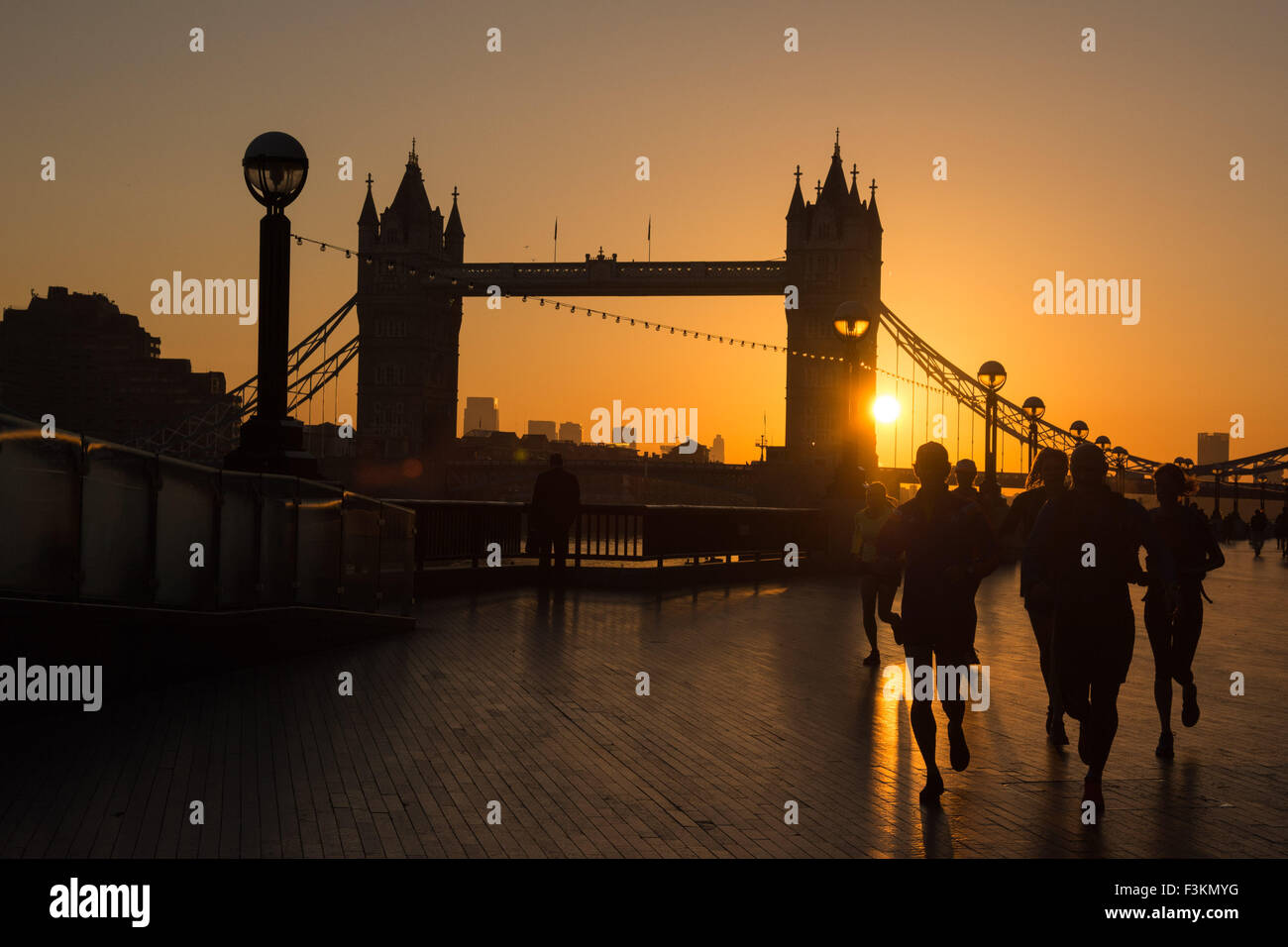 UK weather, London, 9th October 2015. Joggers enjoy their early morning exercise as Tower Bridge is silhouetted against a beautiful sunrise. Credit:  Patricia Phillips/Alamy Live News Stock Photo