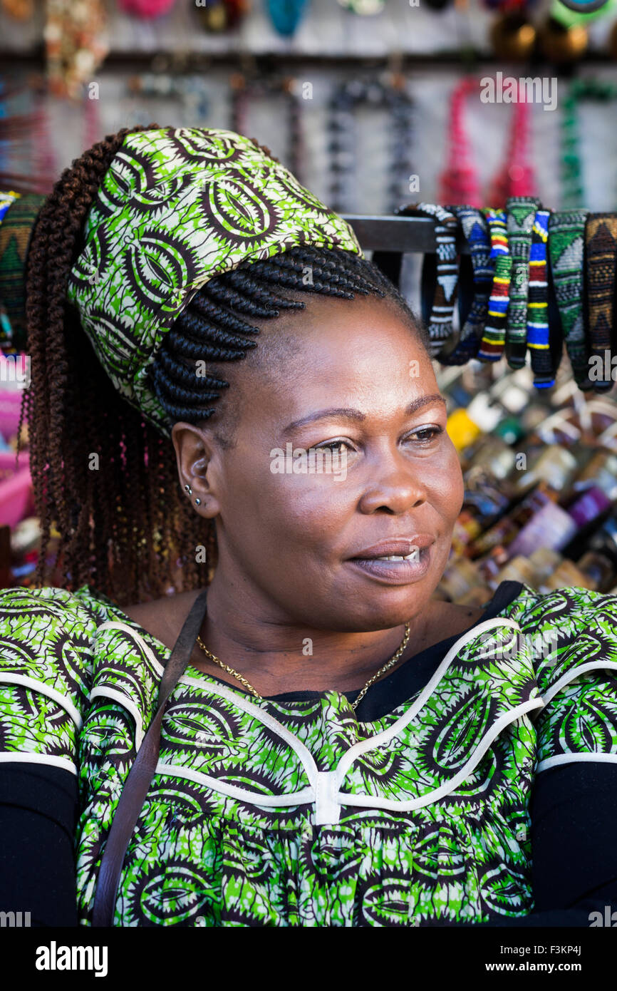 Female vendor with braided hair, green print dress and headscarf at the Market Place, Greenpoint, Cape Town, South Africa Stock Photo