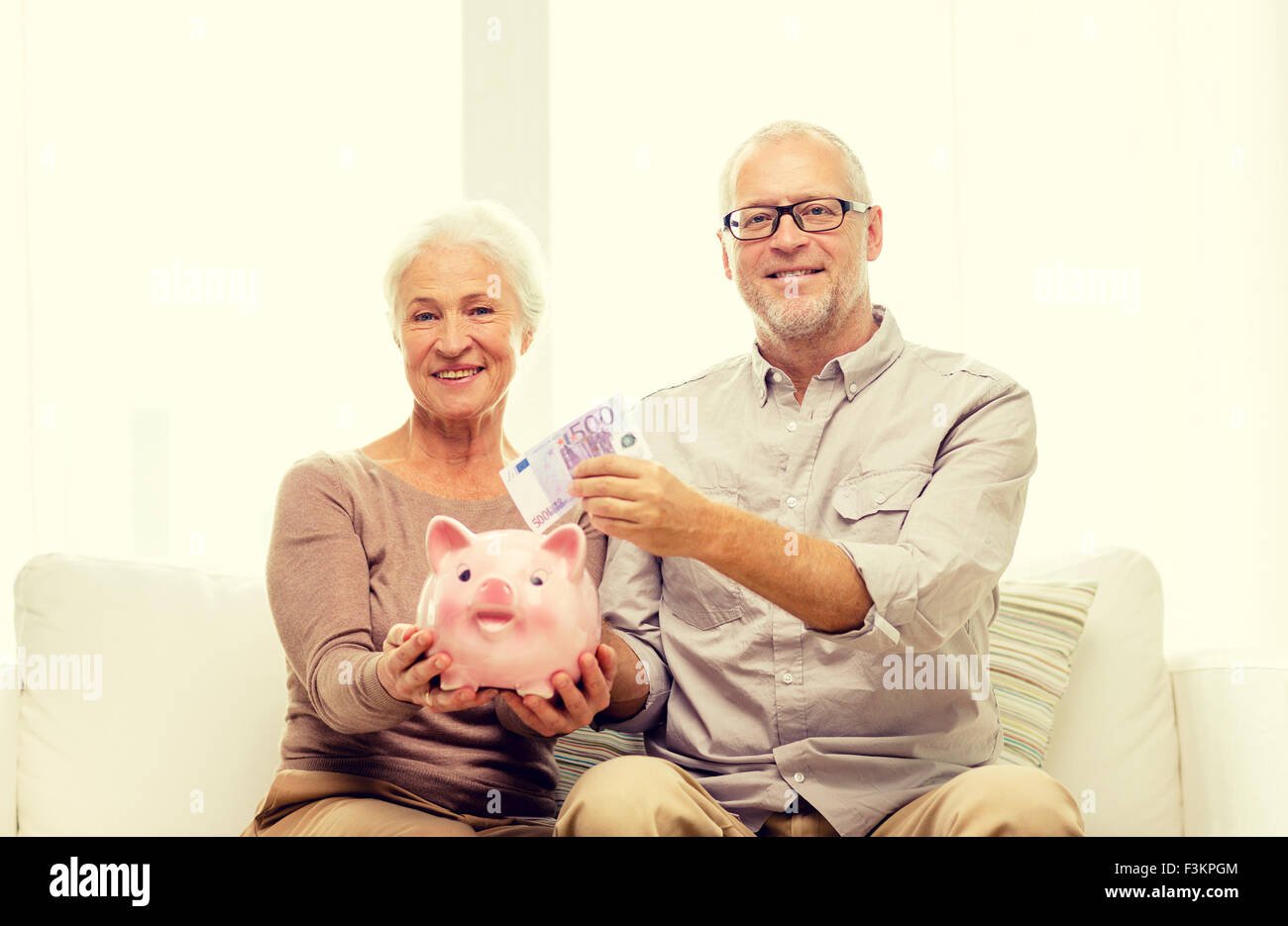 senior couple with money and piggy bank at home Stock Photo - Alamy