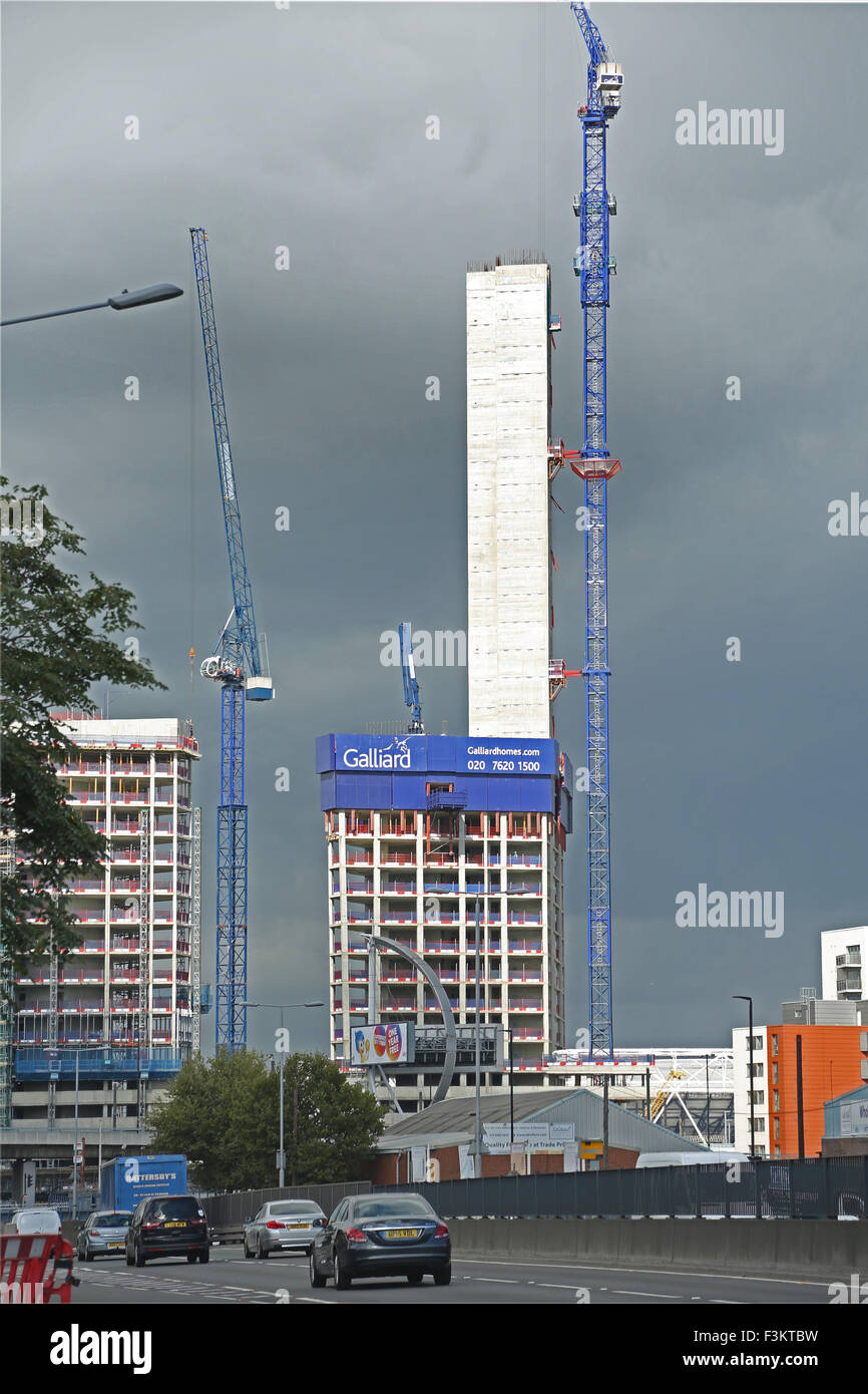 A residential tower block under construction in Bow, East London. The sun highlights the concrete core, dark clouds behind. Stock Photo