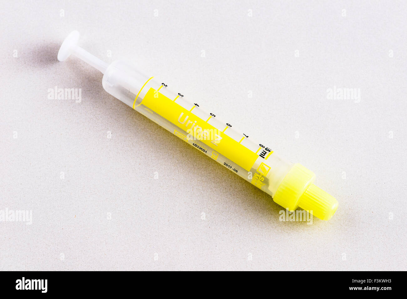 A yellow pharmaceutical phial for medical use, displayed on a white table Stock Photo