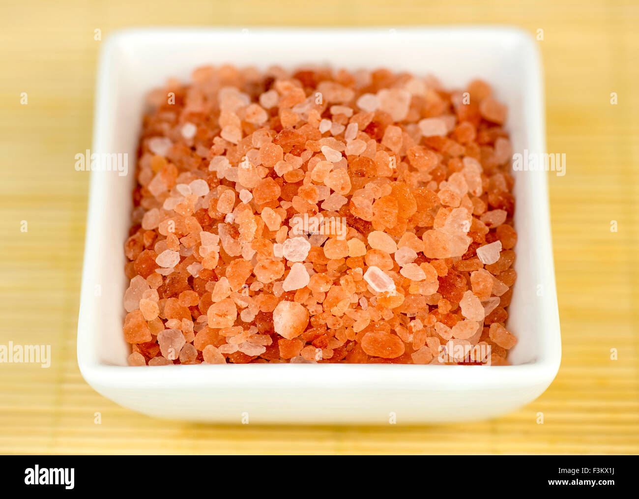 Bowl of pink himalyan rock salt against wooden background Stock Photo