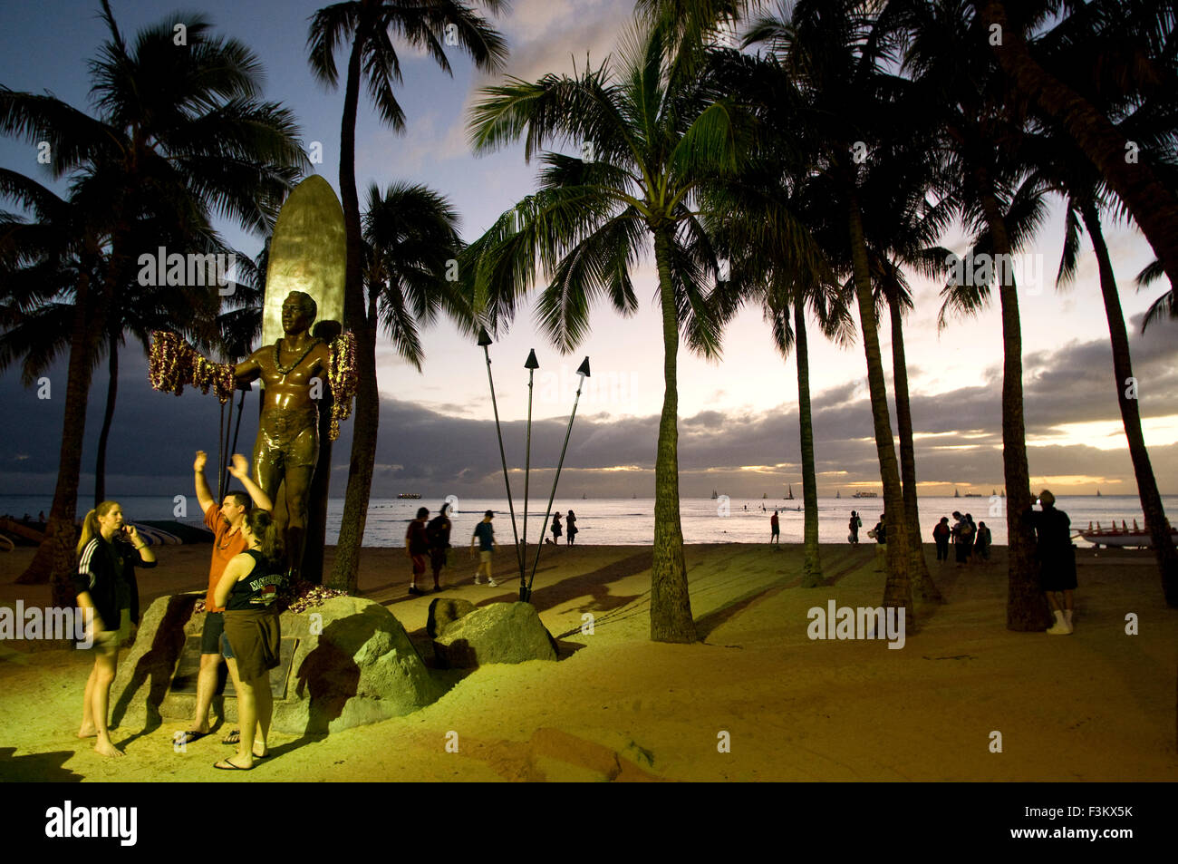 Tourists at night in front of Statue of Duke Kahanamoku, the father of surf that popularized the real sport. Waikiki Beach. O'ah Stock Photo