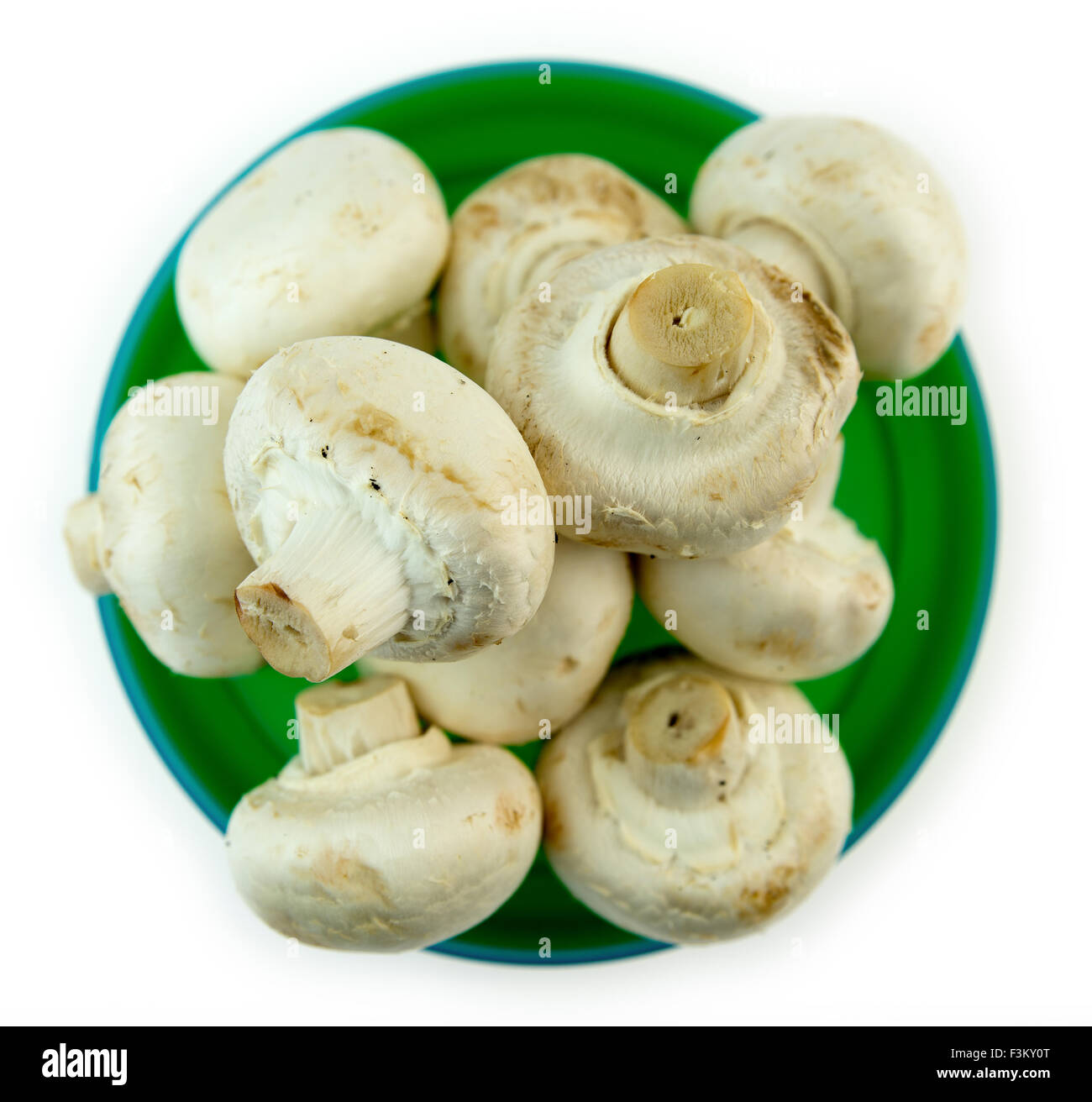 Uncooked mushrooms stacked in green bowl against white background Stock Photo