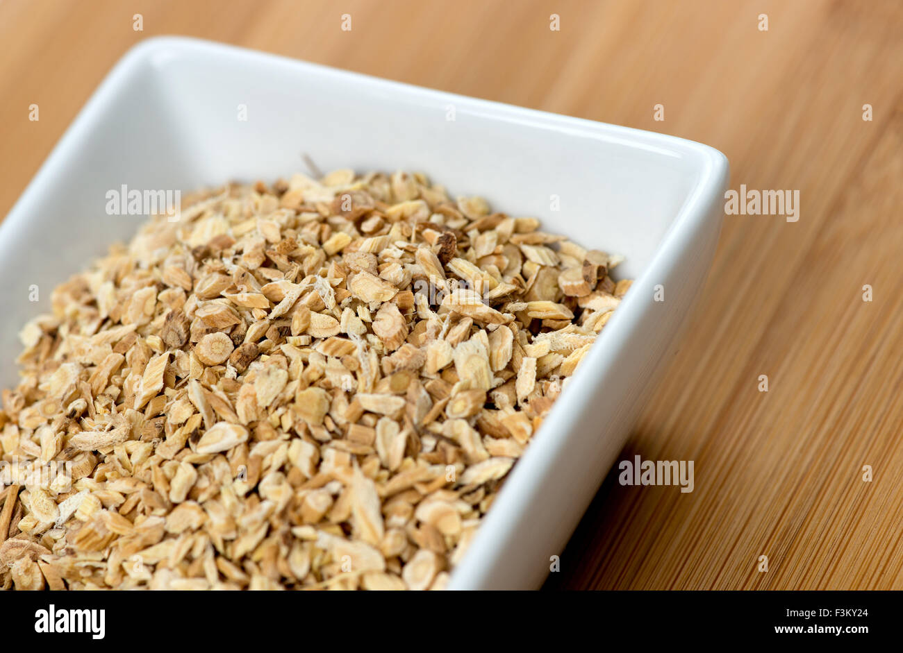 Macro of astragalus root chips against a wooden board Stock Photo