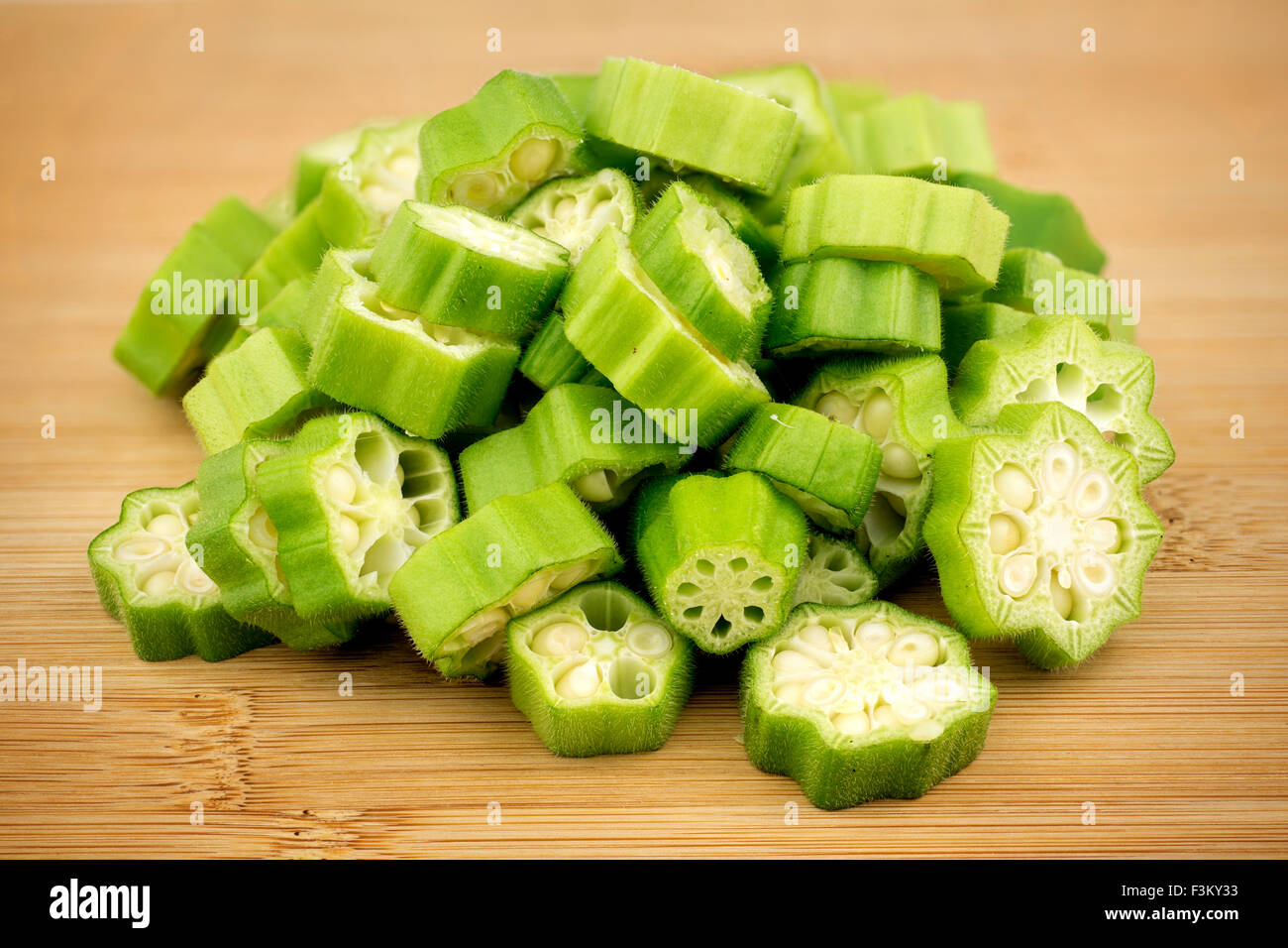 Pile of sliced okra bhindi pieces on rustic wooden background Stock Photo