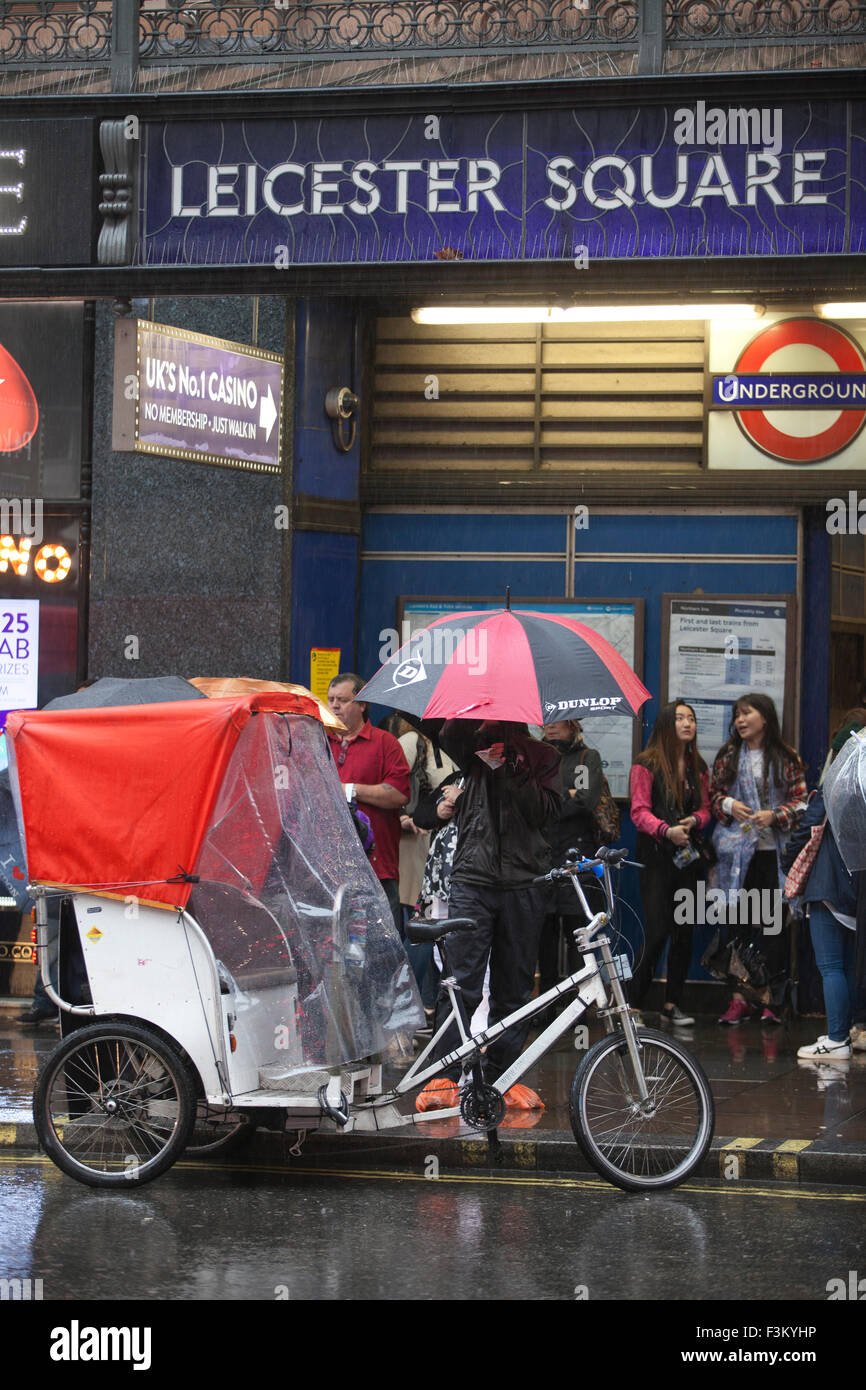 London rickshaw drivers wait outside Leicester Square Underground station for commuters on a wet day, London, England, UK Stock Photo