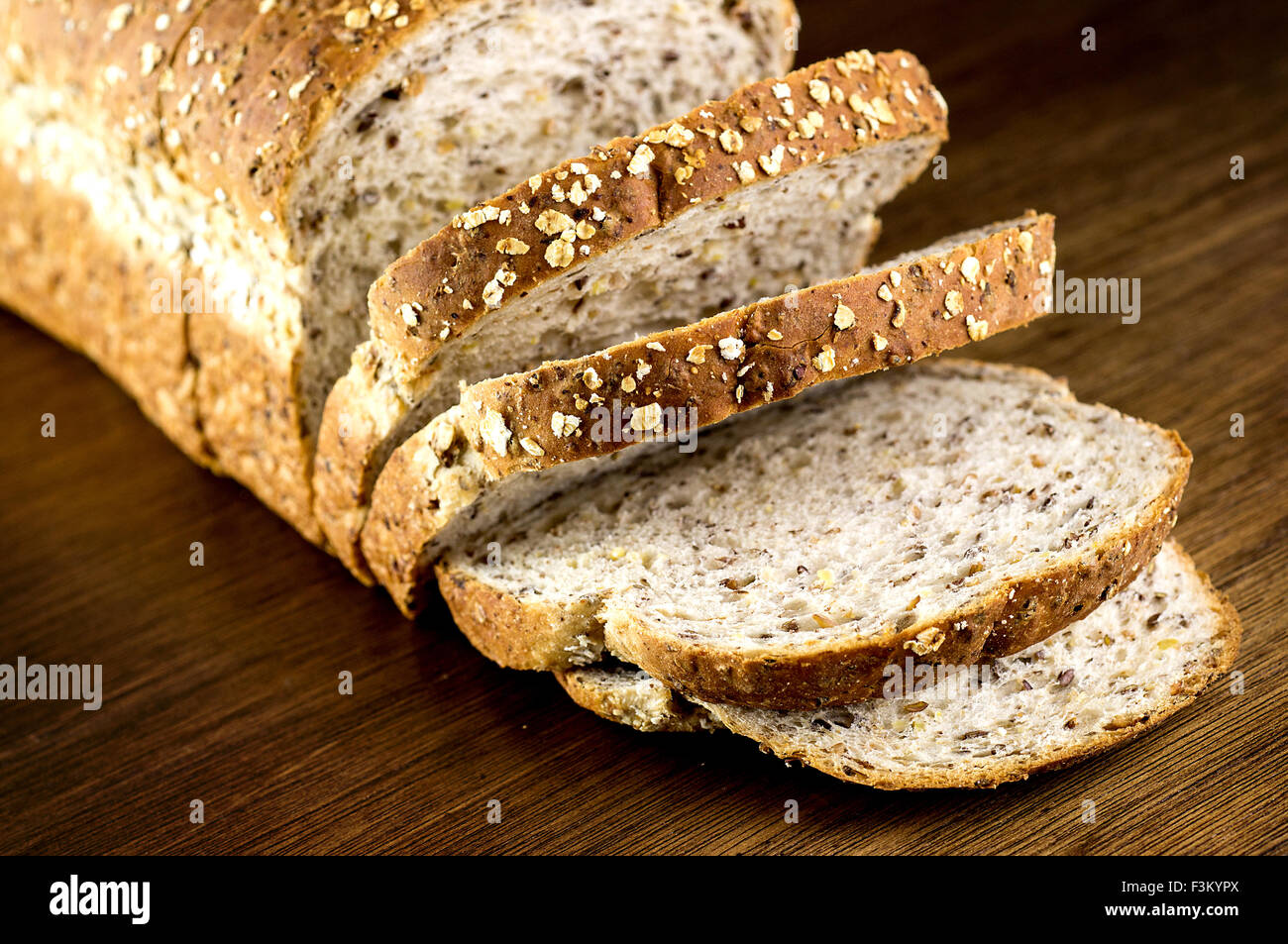 Macro closeup of rustic slices whole wheat multi grain bread on wooden background Stock Photo