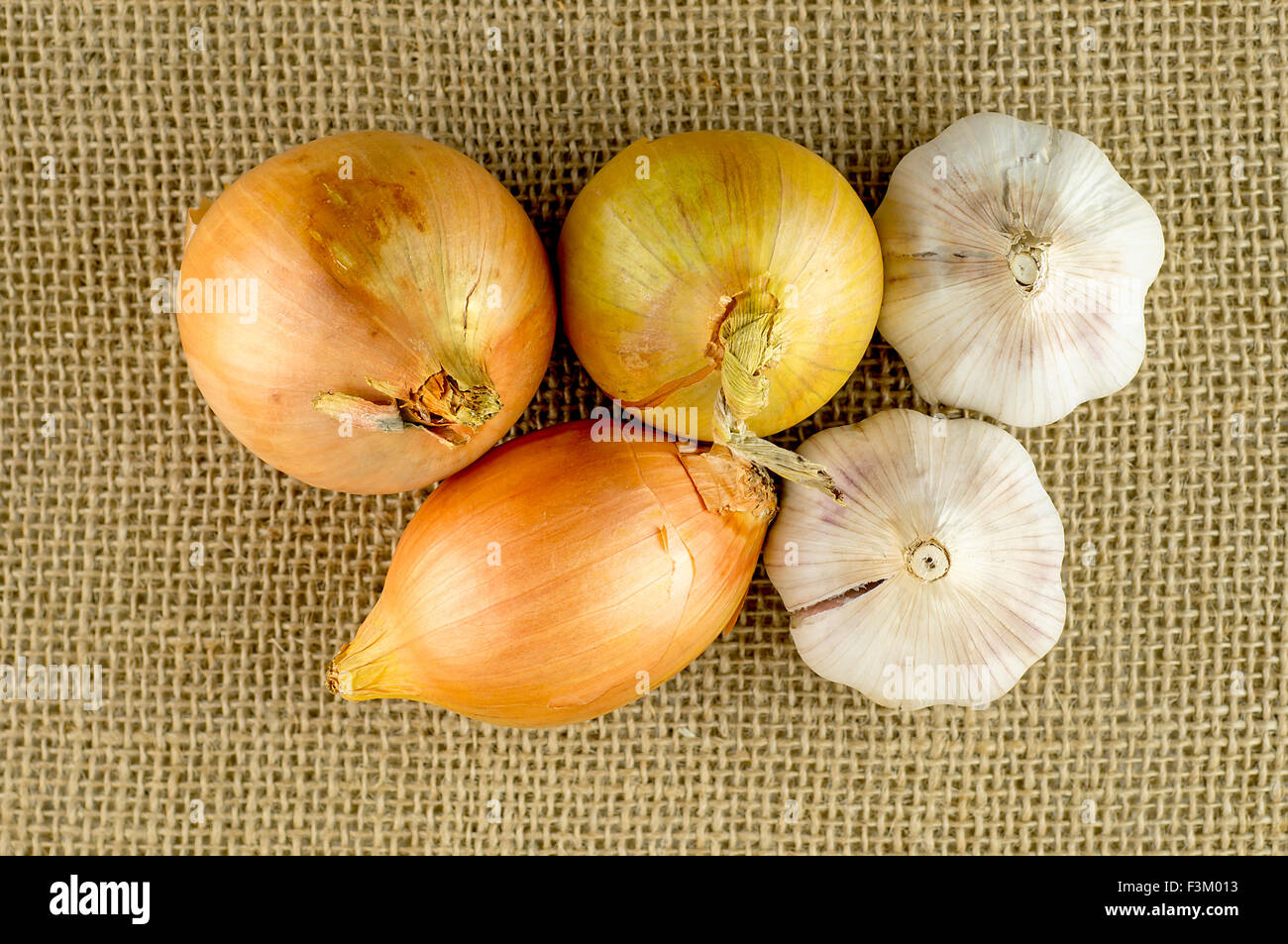 Overhead macro of garlic and onion root veggies on hessian material Stock Photo
