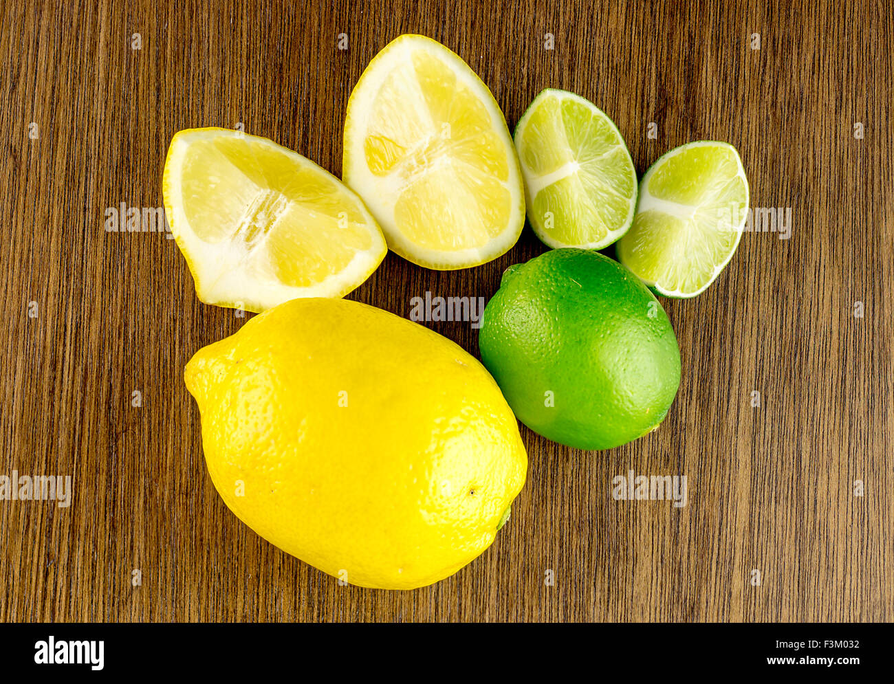 Overhead shot of vibrant ripe green limes and yellow lemons, cut and whole Stock Photo