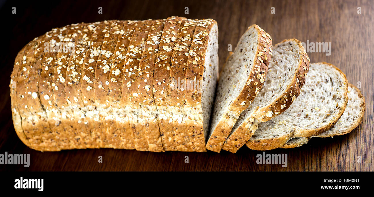 Loaf of multi-grain bread against wood Stock Photo