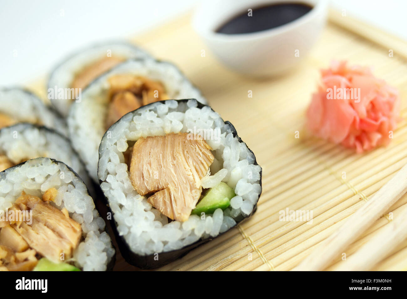 Macro of teriyaki sushi maki rolls on a bamboo mat with ginger and soy sauce Stock Photo