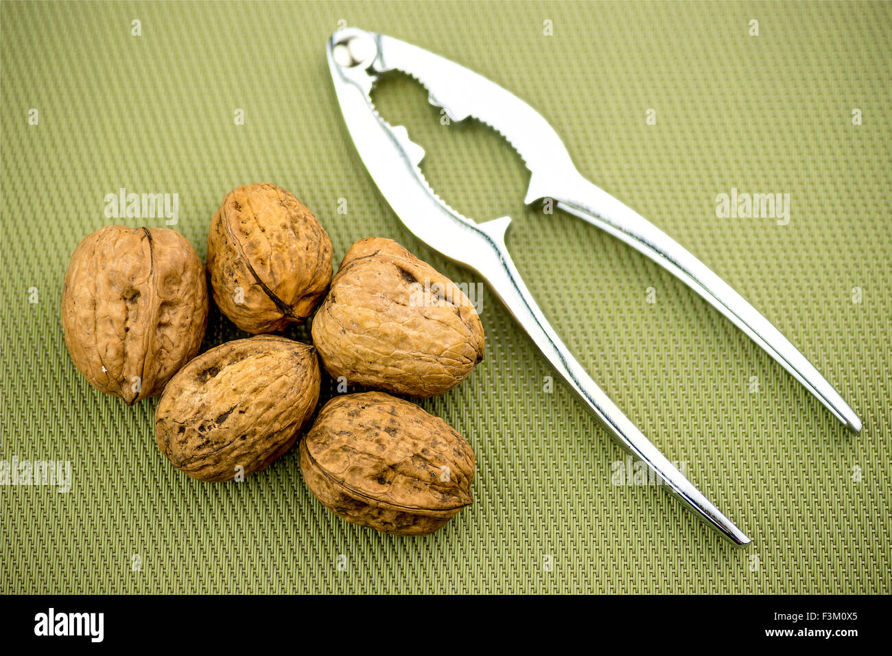 Walnuts in shells with nut cracker Stock Photo