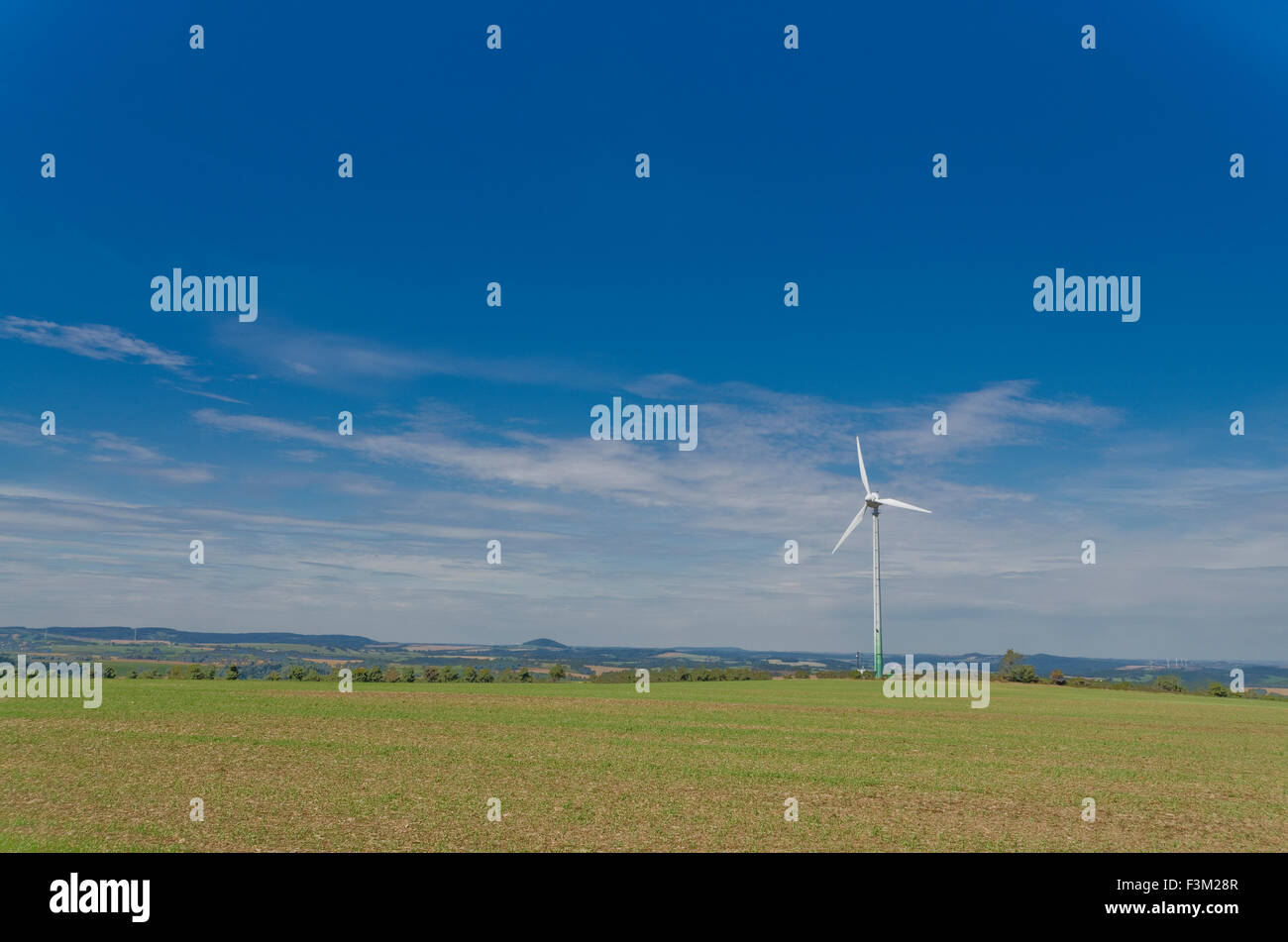 A wind power plant in agriculture landscape with blue sky Stock Photo