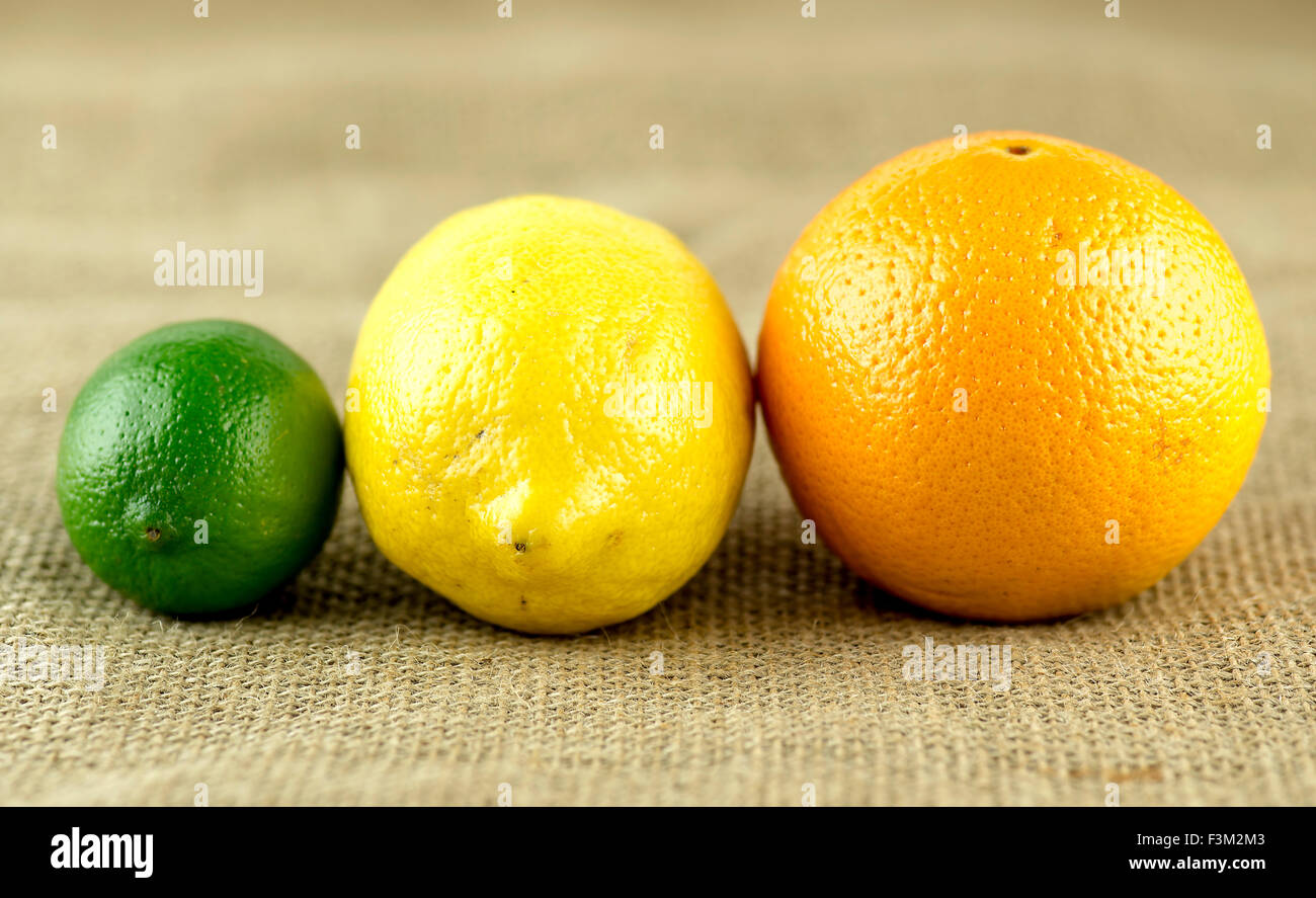 Colorful set of citrus fruits with orange, lemon and lime on hessian burlap background Stock Photo