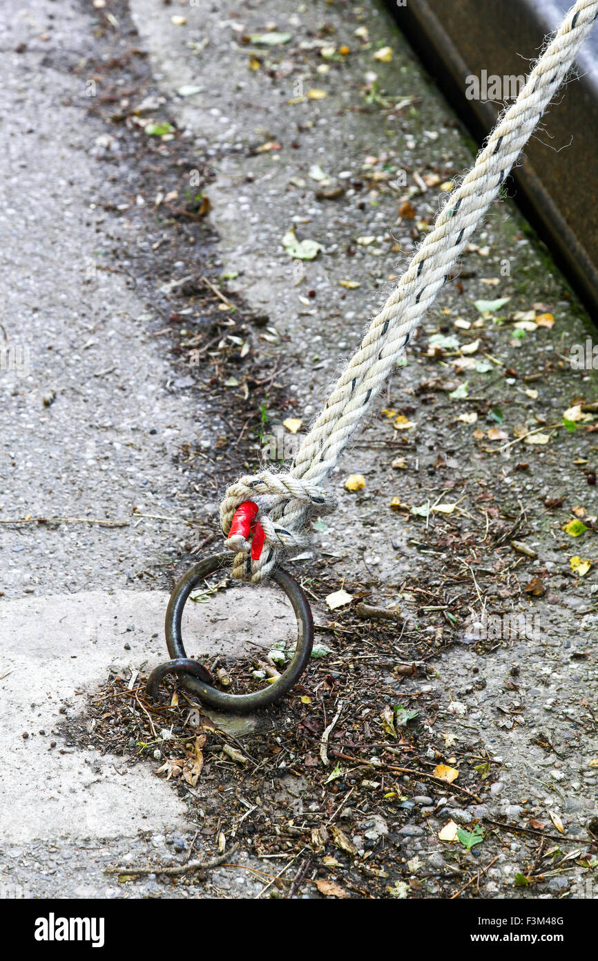 A rope tied to a mooring ring by the side of a canal Stock Photo