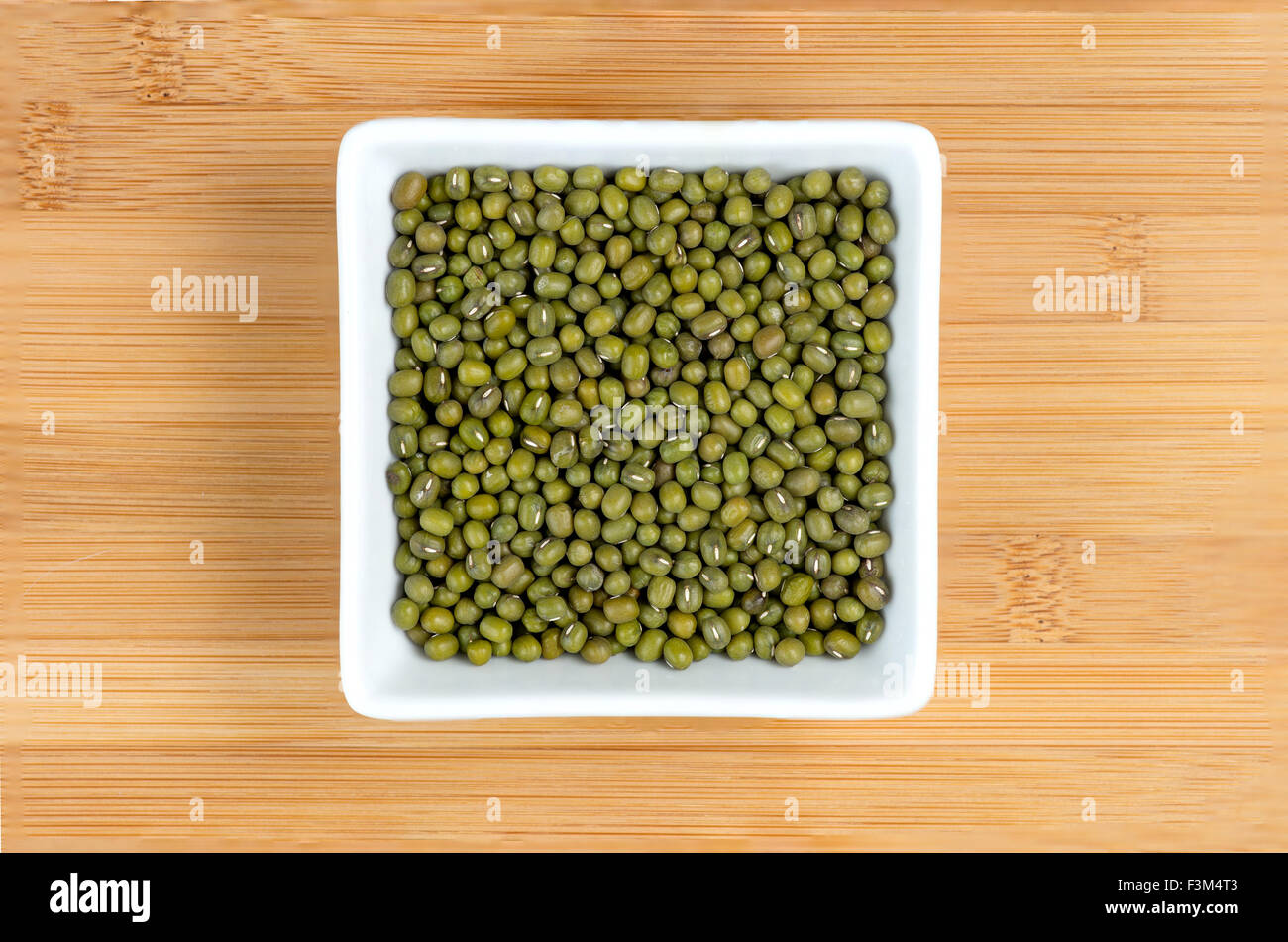 Green mung beans in white bowl on wooden board Stock Photo