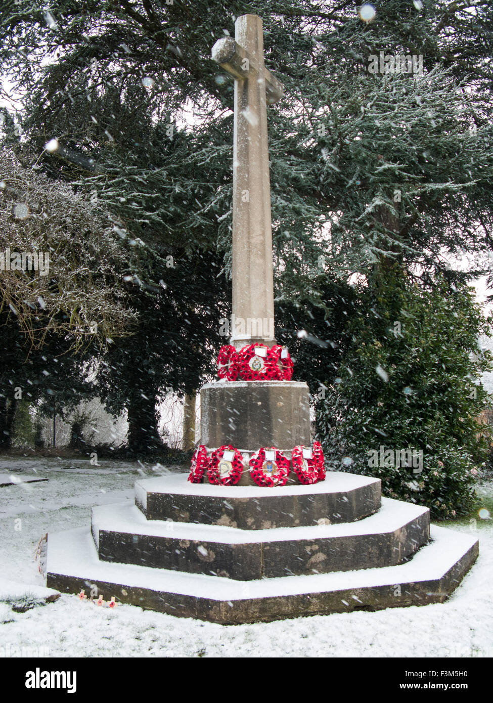 wintry war memorial with snow falling and red poppies Stock Photo