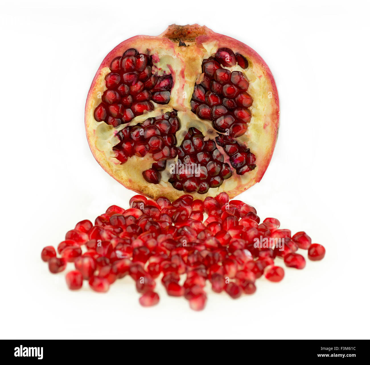 Pomegranate cut in half with seeds spilling out, isolated on a white background Stock Photo