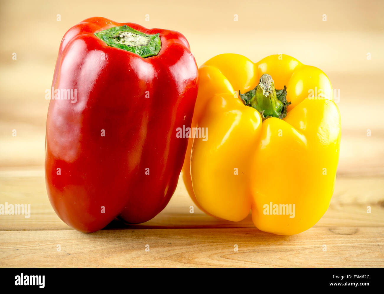 Colorful, vibrant red and yellow capsicum on wooden chopping block Stock Photo