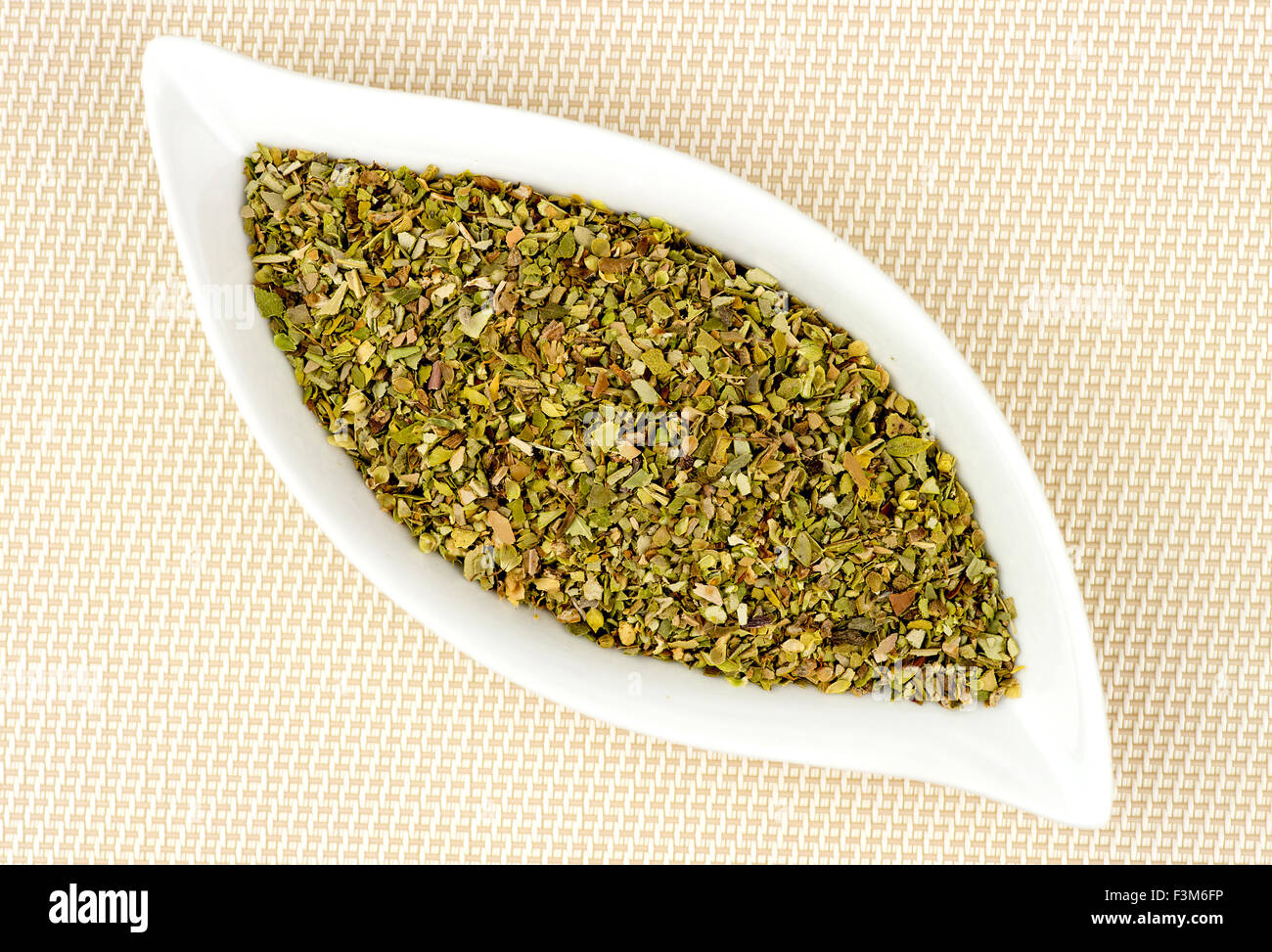 Dried and chopped oregano in stylish glass container Stock Photo