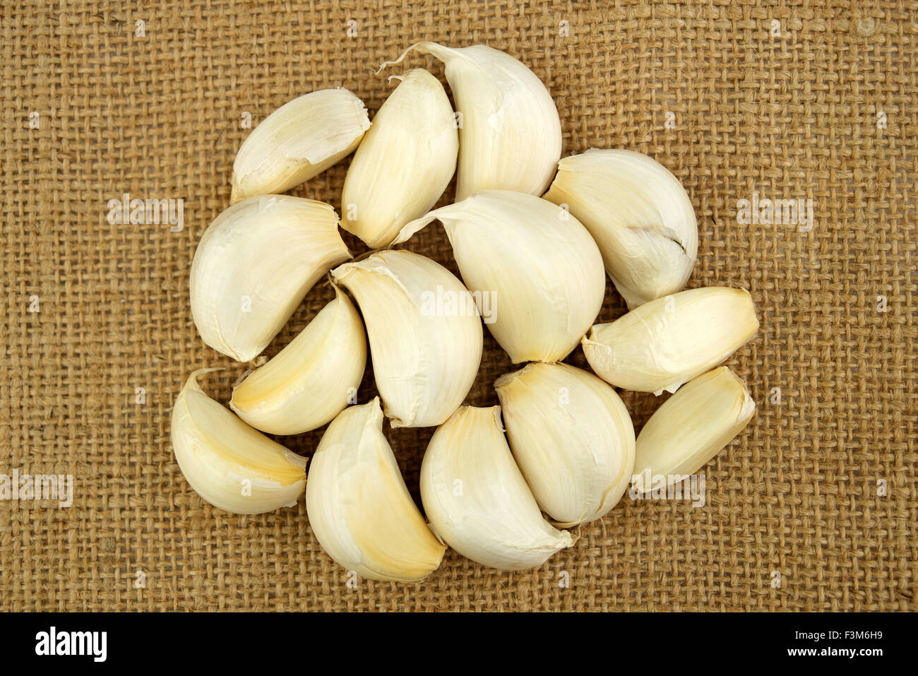 Pile of unshelled garlic cloves against a sack textured background Stock Photo