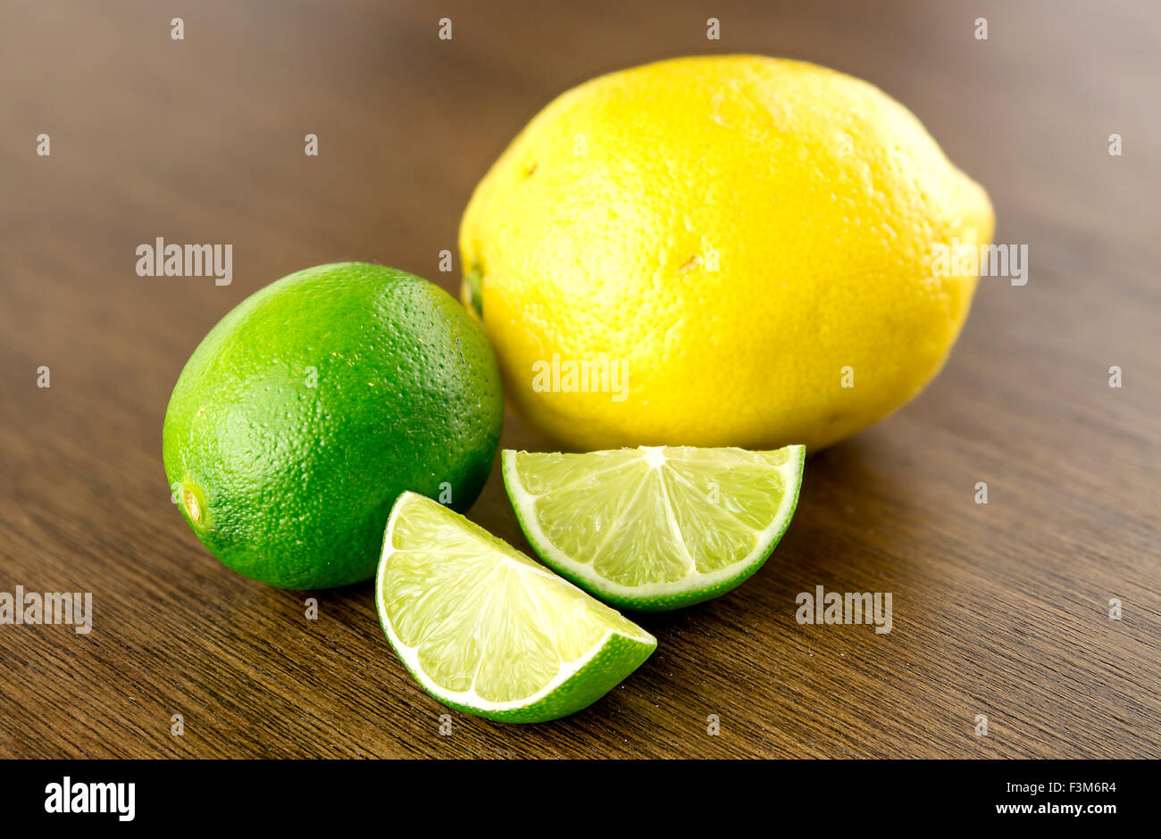 Cut limes and lemon on wooden background Stock Photo