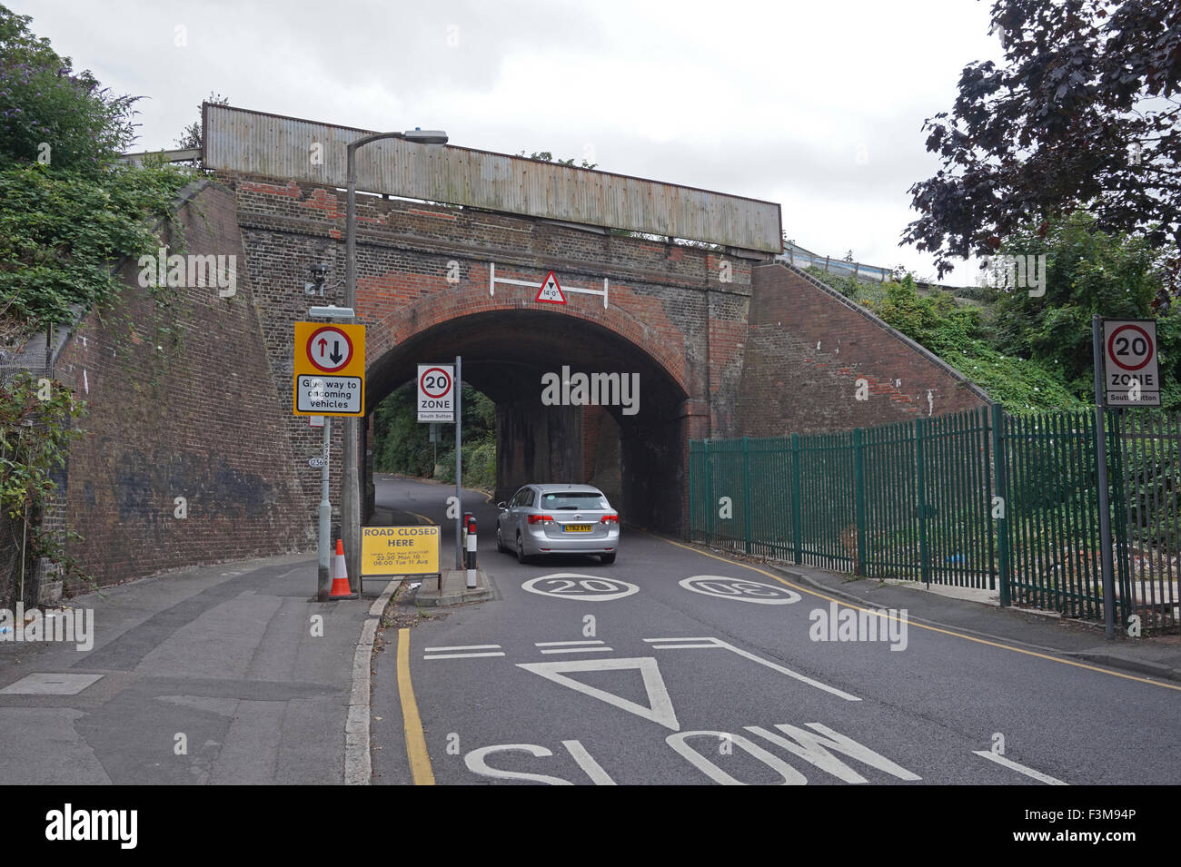 A car going through a single-track road under a railway bridge, Sutton, Surrey Stock Photo