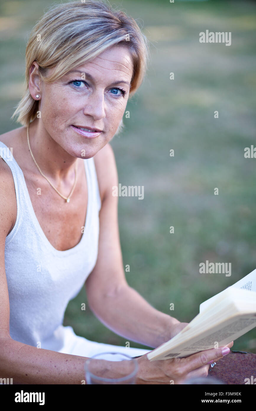 Cute woman reading a book outdoor sitting on a garden chair Stock Photo ...