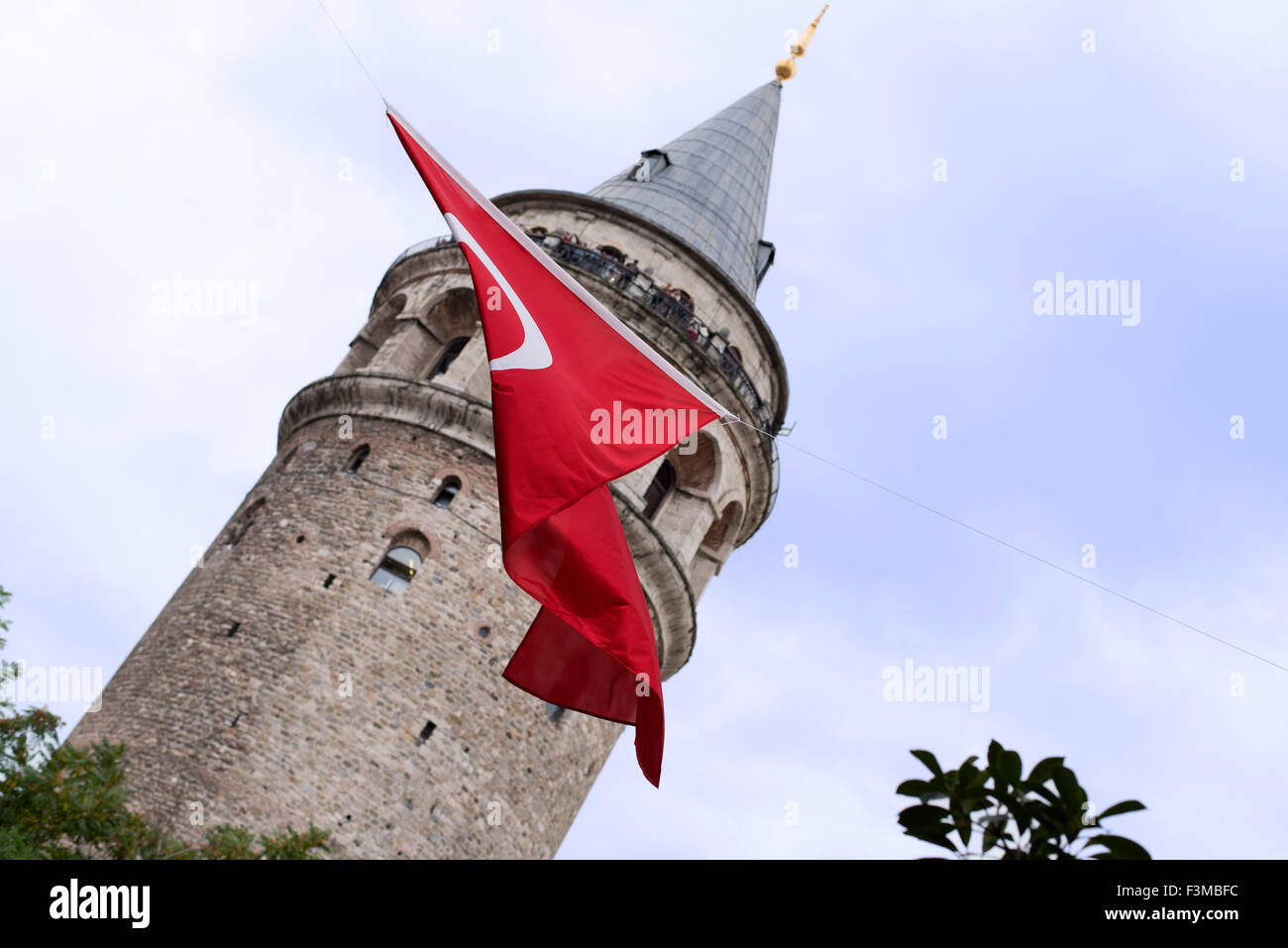 Red Turkish crescent flag flying in front of the Galata Tower in Istanbul Turkey. Stock Photo