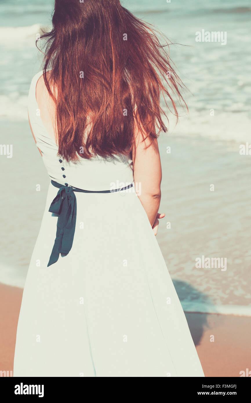 Historical young woman on the beach wearing a blue dress Stock Photo