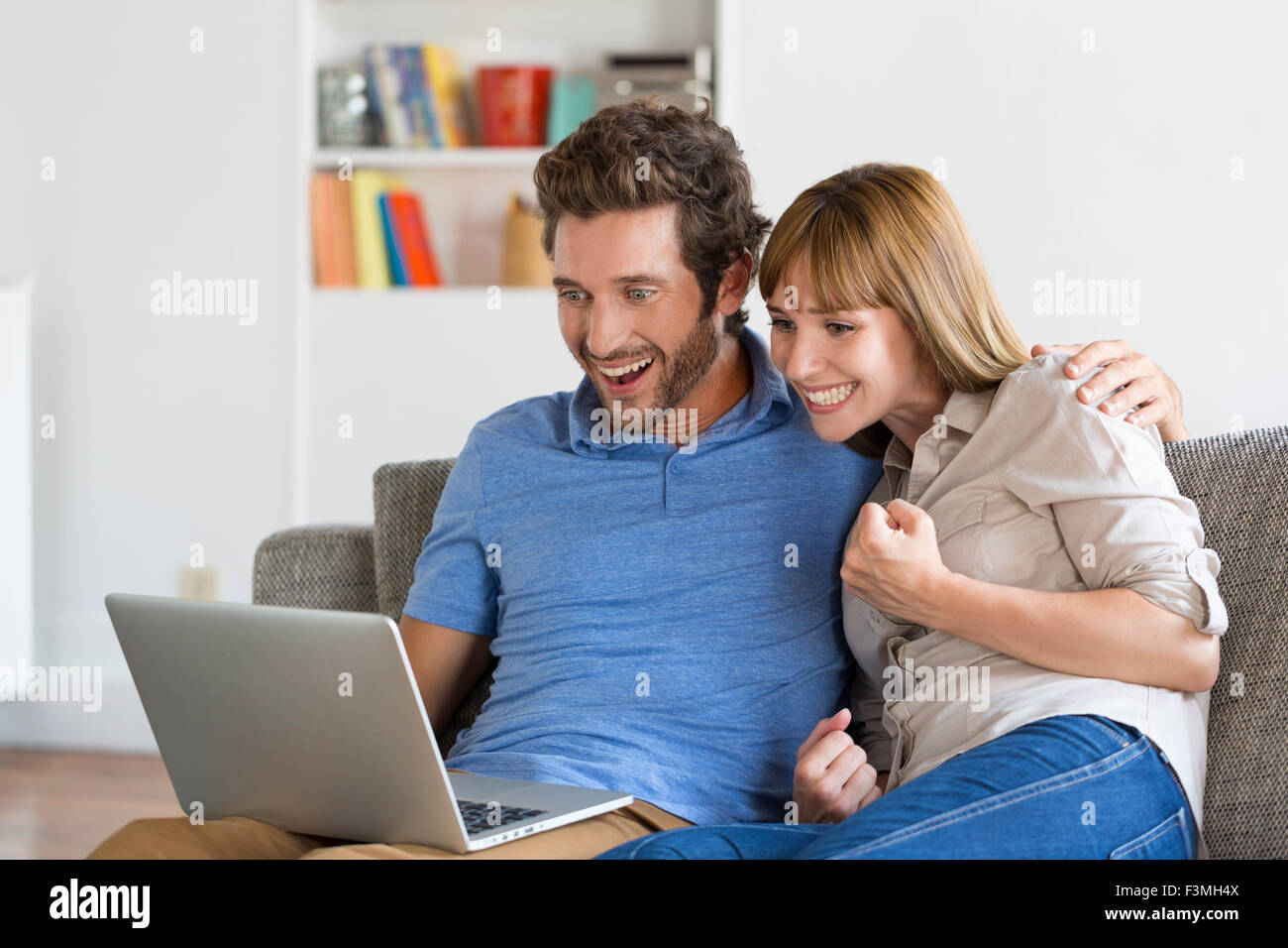 Young couple consult the results of the lottery on laptop in modern white home. Stock Photo
