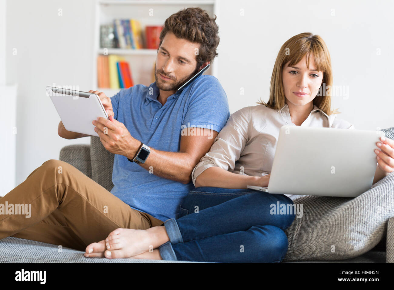 Digital geek couple. Mobile phone, smartwatch, tablet. Modern white apartment Stock Photo