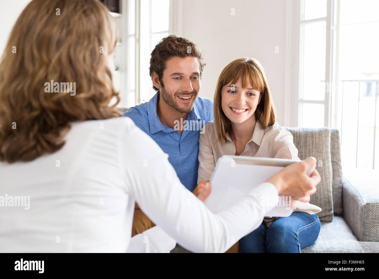 Architect presenting a new project on digital tablet to a cheerful young couple in office Stock Photo