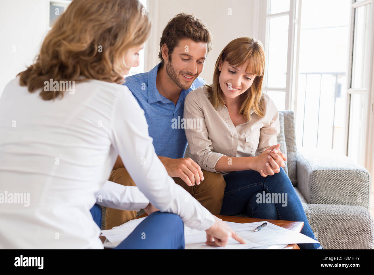 Real estate agent presenting a contract for house investment to future owners couple Stock Photo