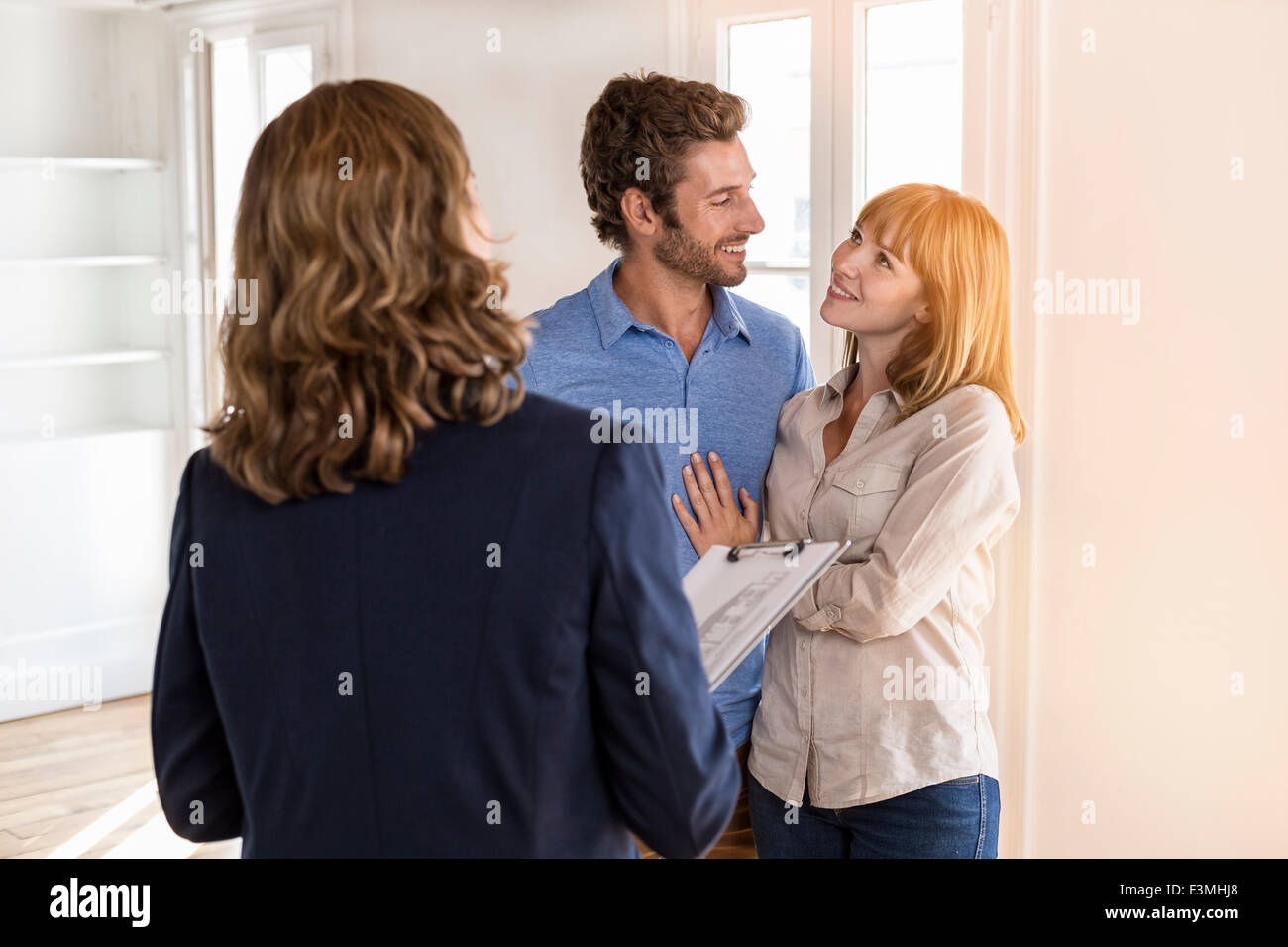 Real estate agent showing modern white apartment to future owners couple Stock Photo