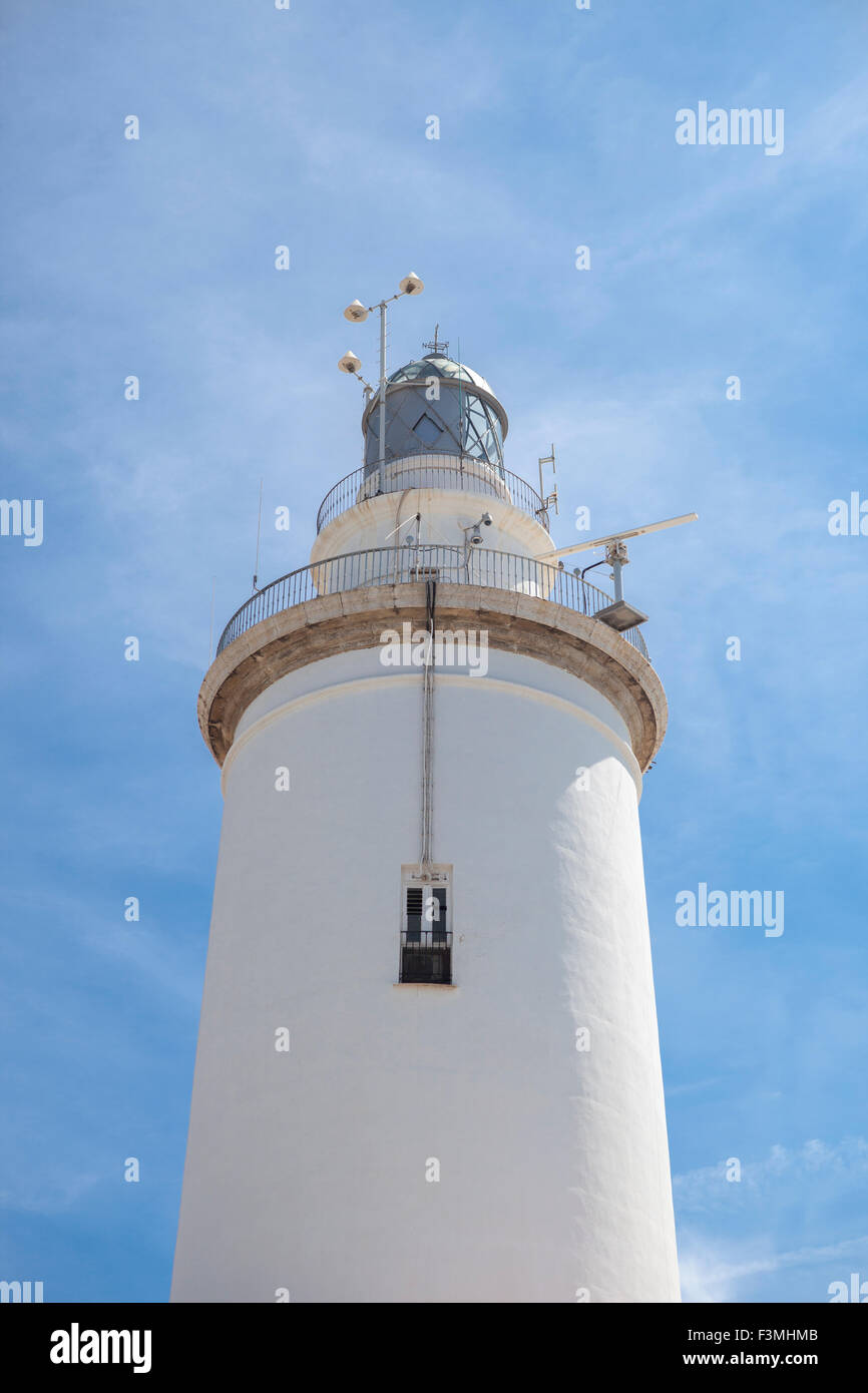 A white whitewashed lighthouse isolated over blue sky with clouds Stock Photo